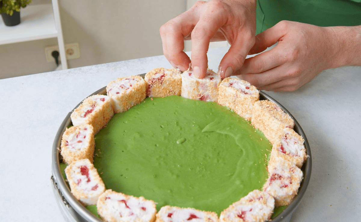Die Kokospudding-Röllchen werden hochkant in die Matcha Frischkäsecreme gedrückt