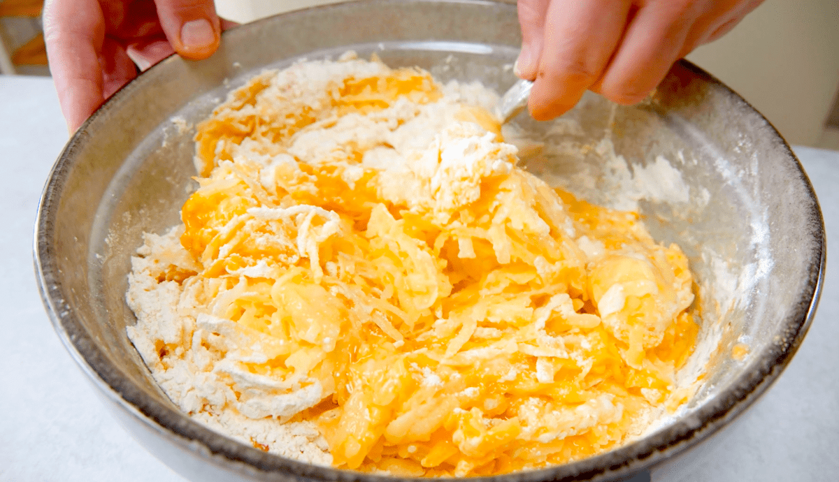 Geraspelte Kartoffeln werden in einer Schüssel mit anderen Zutaten vermengt.