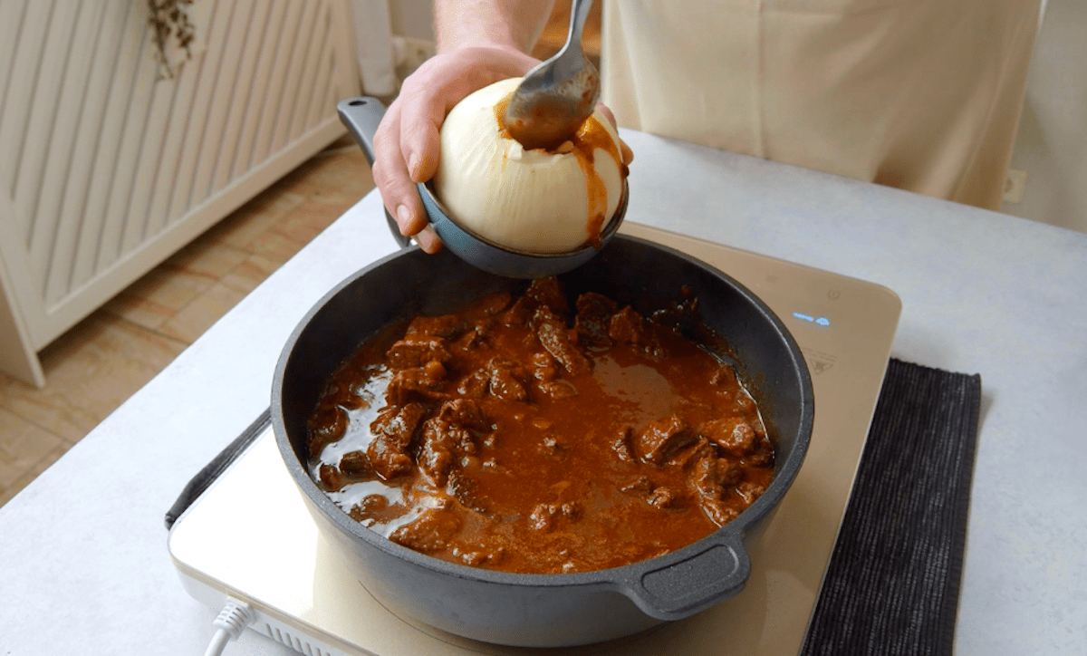 Eine augehöhlte Zwiebel wird mit Rinderragout gefüllt