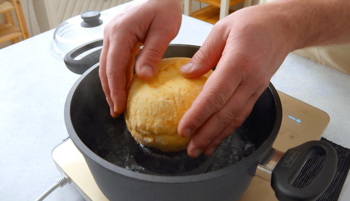 Die mit Rinderragout gefüllte Zwiebel in Kloßteig wird in einen Topf gesetzt