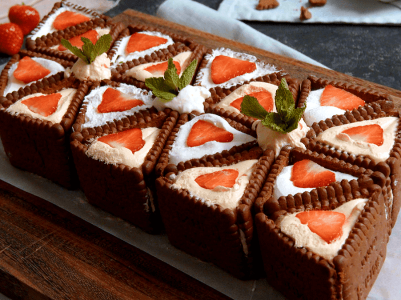 No-bake-Kuchen-mit-Butterkeksen, angerichtet auf einem Backpapier und Brett.