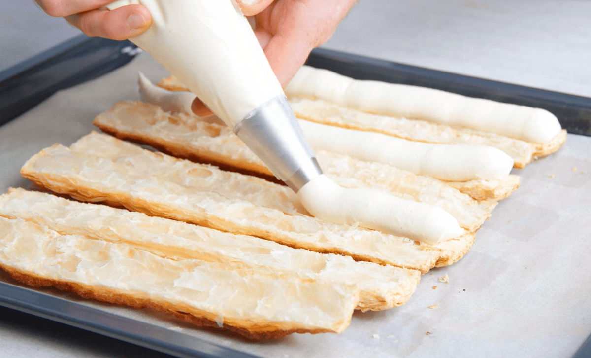 Vanillecreme wird auf gebackene BlÃ¤tterteigstangen gegeben