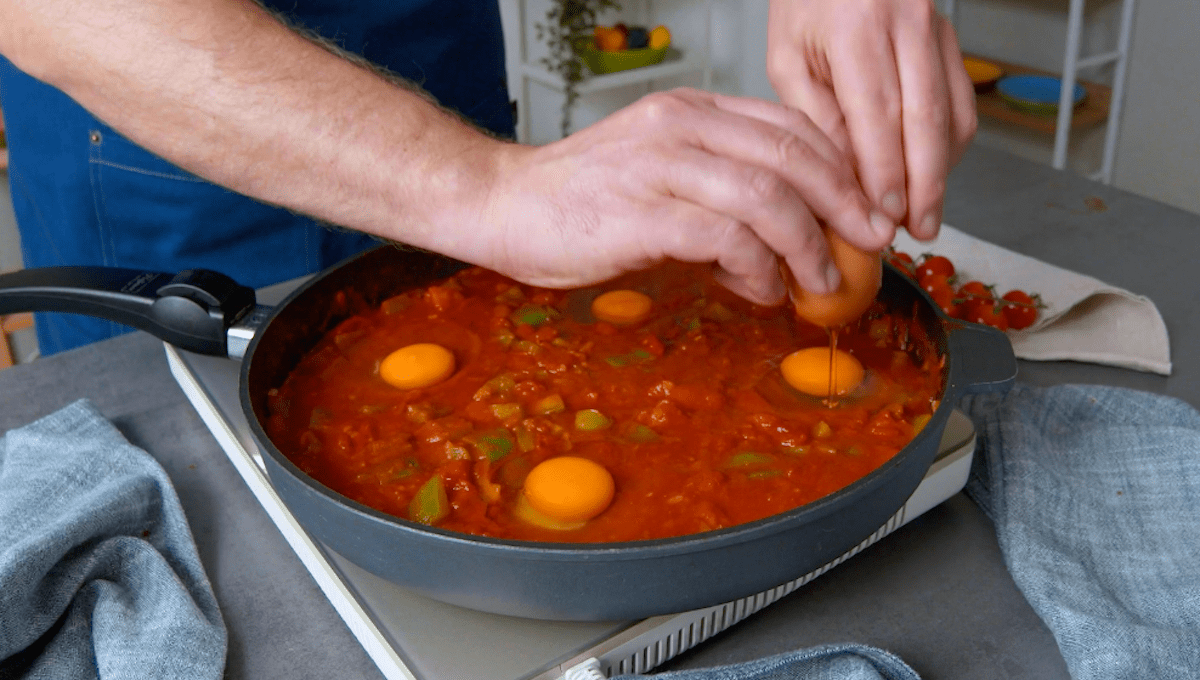 Eier werden in Tomatensauce in eine Pfanne gegeben