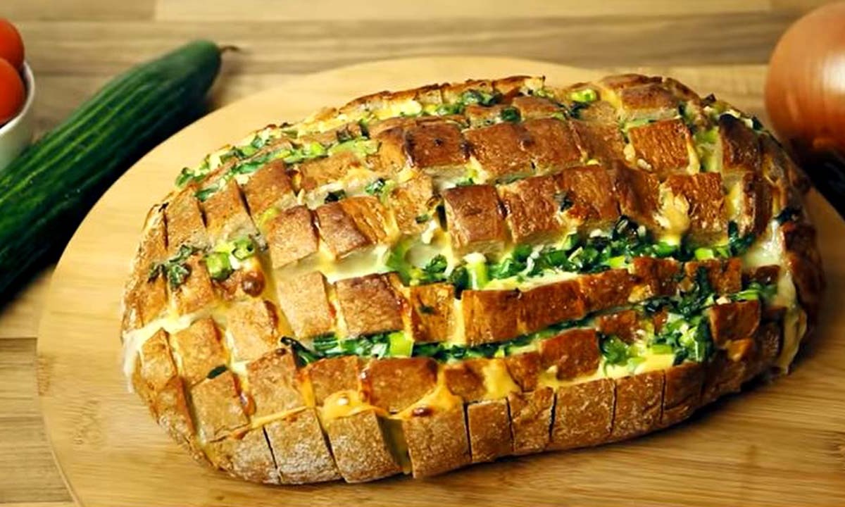 Ein Zupfbrot mit Käse und Knoblauchbutter auf einem Holzbrett.
