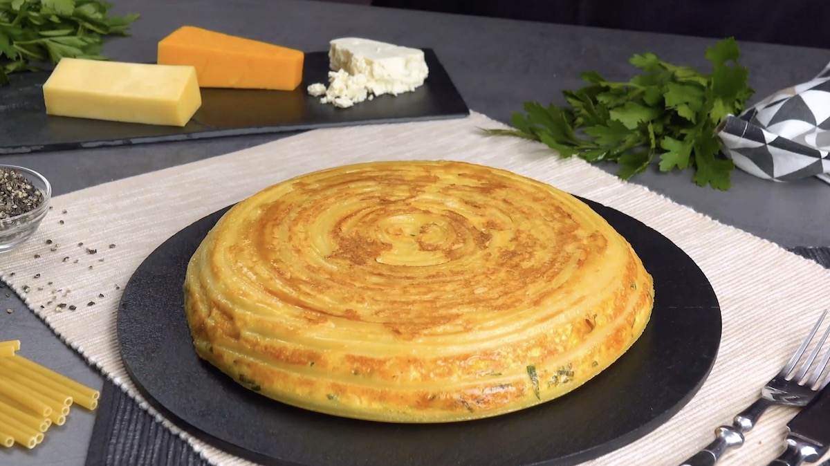 Rundes Nudel-Omelett mit KÃ¤se auf Schieferplatte