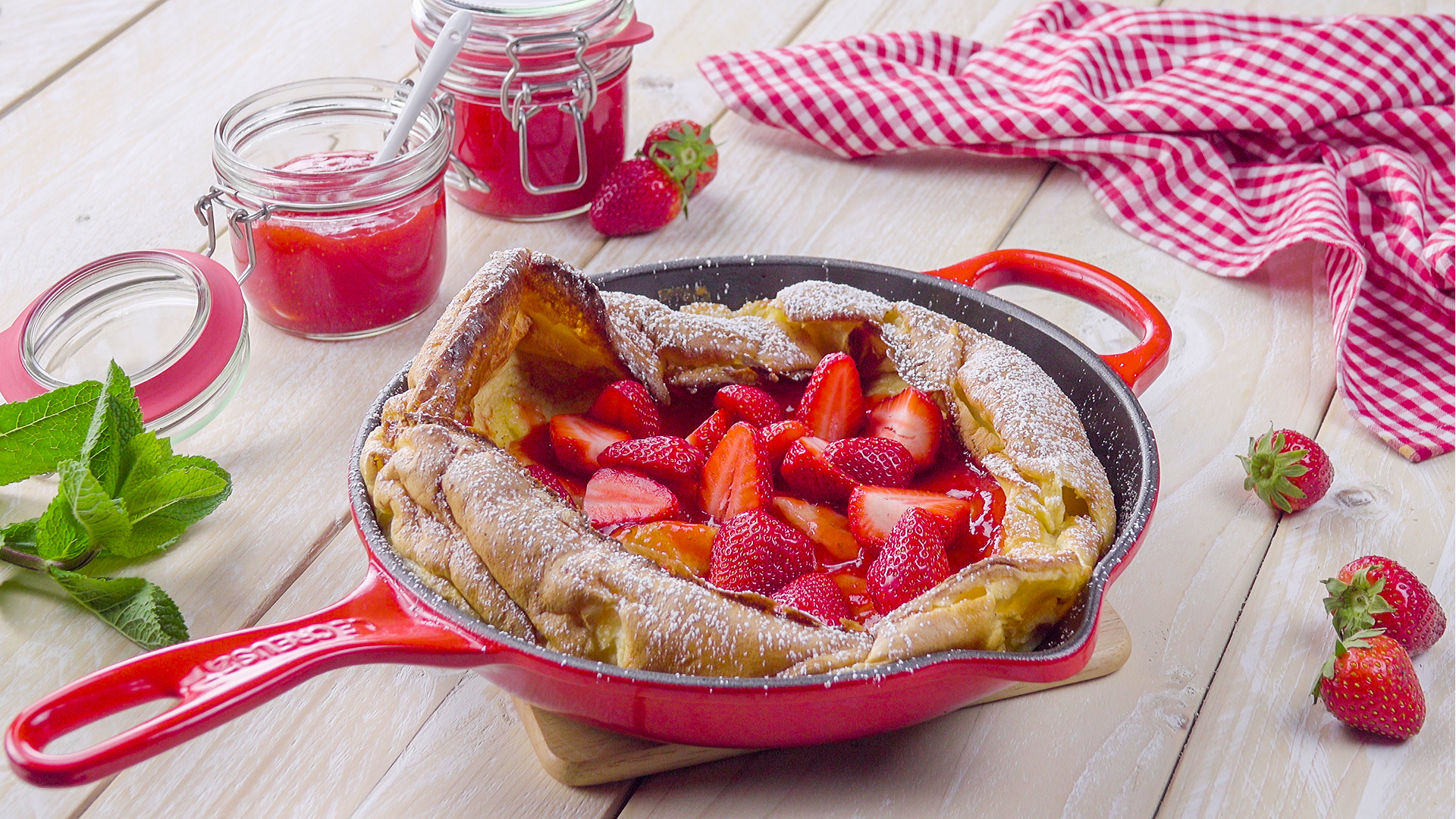 Riesiger Ofen-Pfannkuchen mit frischen Erdbeeren in rosafarbener Pfanne