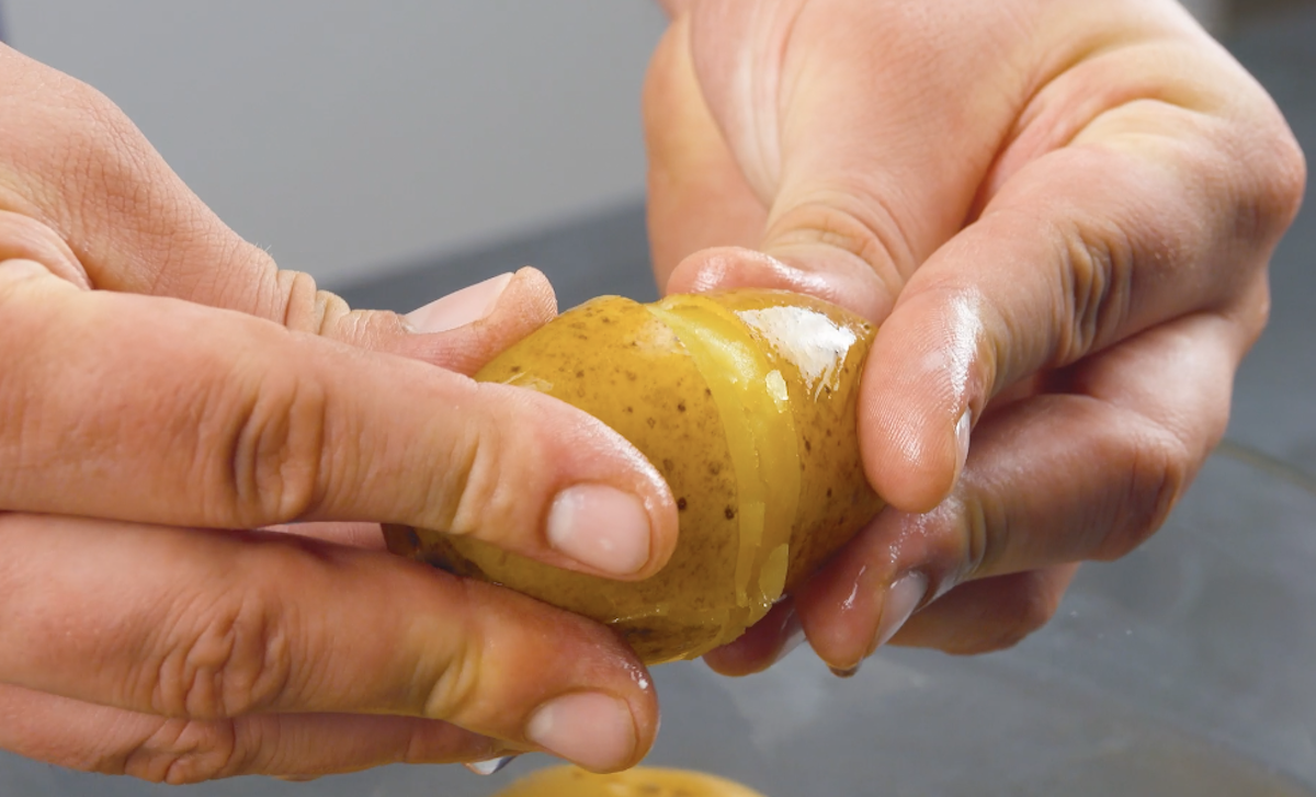 Zwei Hände halten eine Kartoffel mit Schale in der Hand