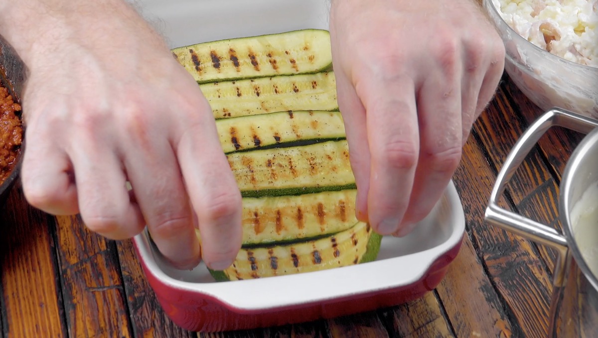 Angebratene Zucchinischeiben werden in Auflaufform gelegt