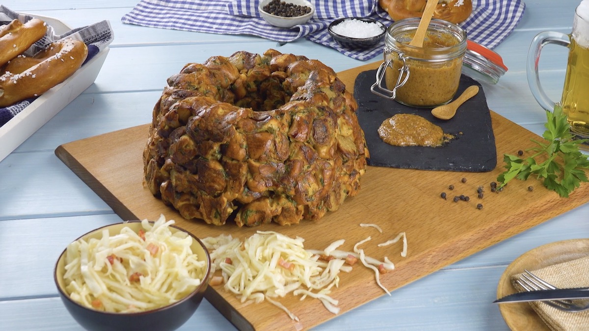 Herzhafte Gugelhupf aus Brezeln und BratwÃ¼rsten auf Holzbrett mit sÃ¼ÃŸem Senf und Krautsalat