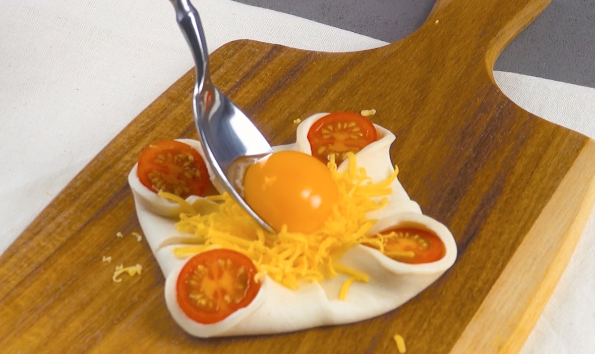 Nach dem Zusammenschlagen der Ecken kommen Cheddar und Eigelb in die Mitte
