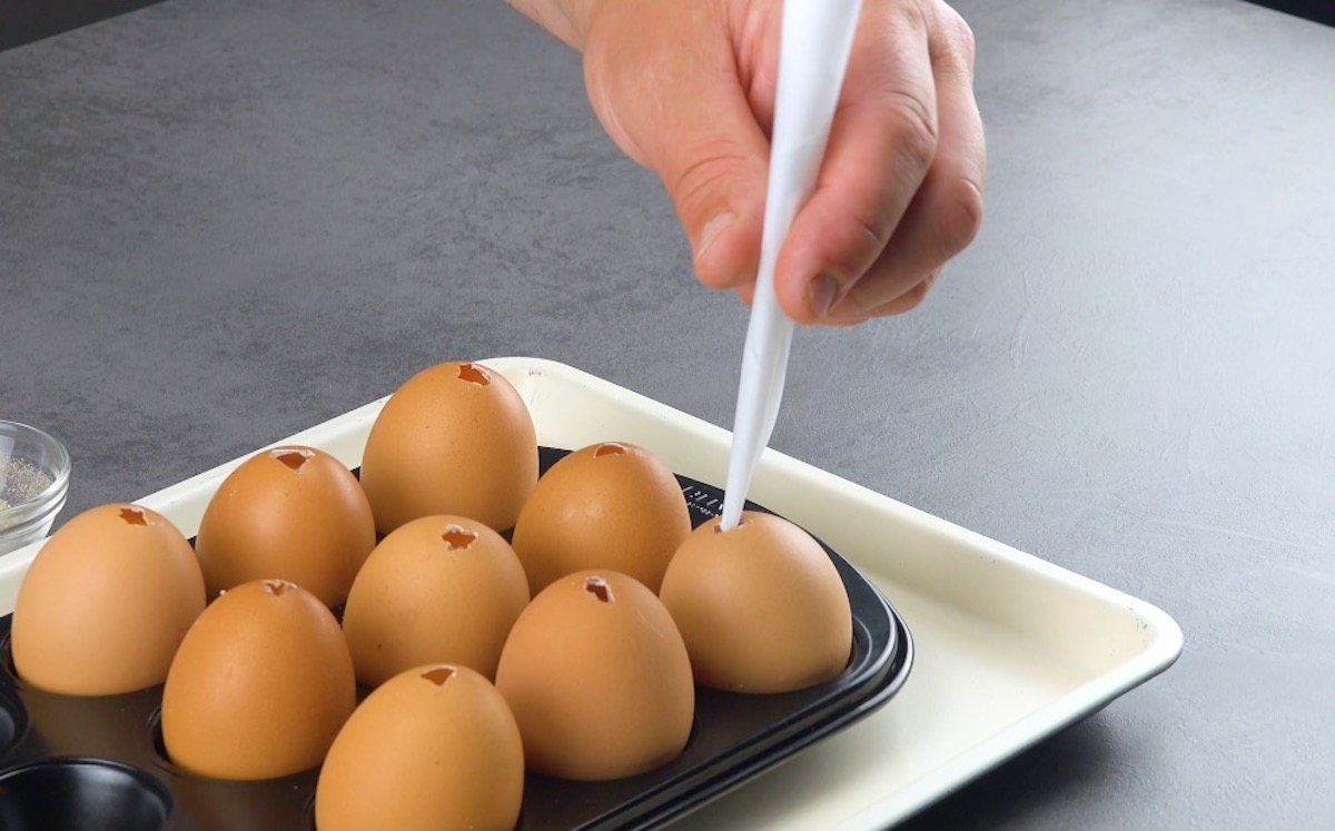 Trichter aus Backpapier wird in Ei in Muffinform gesteckt