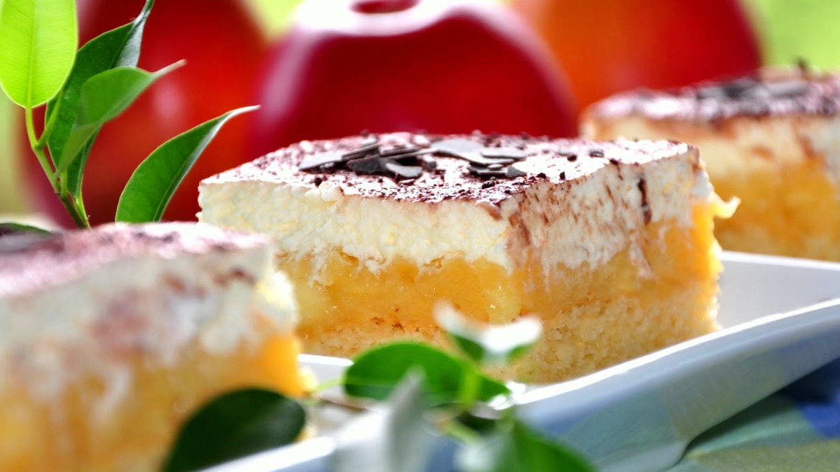 3 Stücken Apfelmus-Schmand-Kuchen auf einer Servierplatte, im Hintergrund rote Äpfel.