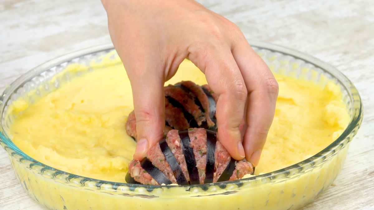 Die Zwischenräume in den Auberginen werden mit Hackfleisch gefüllt und auf den Kartoffelbrei gelegt