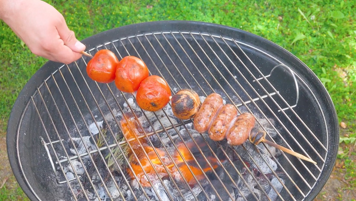Salsiccias, Zwiebel und Tomaten auf HolzspieÃŸ  werden auf Grill gerÃ¶stet