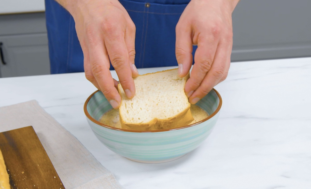 Toastscheiben werden durch Milch-Eier-Mischung gezogen