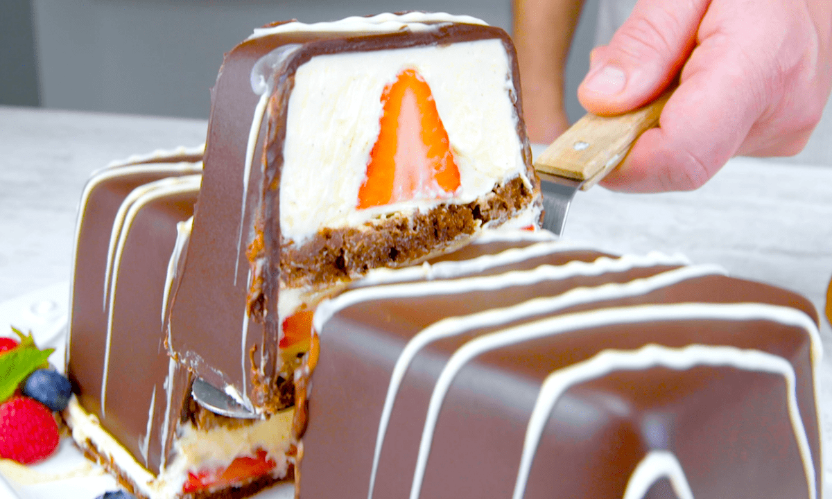 Schoko-Dessert mit Vanillecreme und Erdbeeren, aus dem ein Stück geschnitten wird.