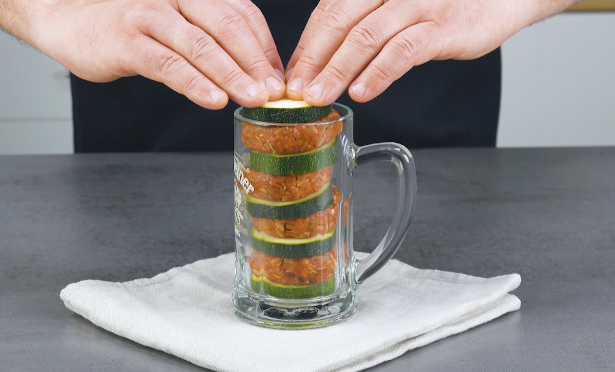 Zucchinischeiben und Hackfleisch werden abwechselnd in Bierglas gestapelt