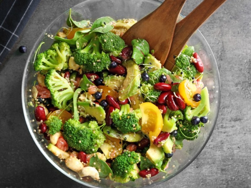 Eine Schüssel Brokkolisalat mit Salatbesteck aus Holz.