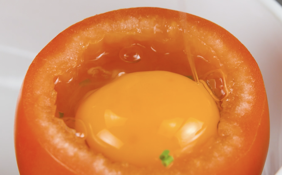 Ein Ei wird in eine ausgehÃ¶hlte Tomate gegebene