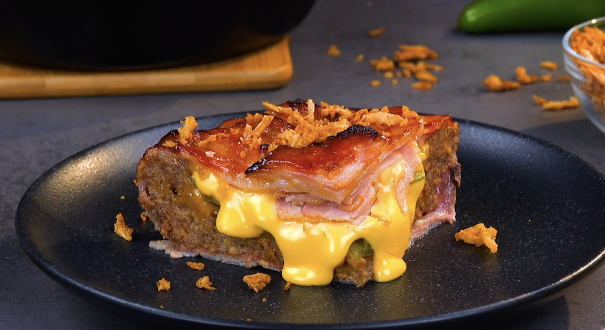 Ein Stück herzhafter Kuchen mit Bacon, Hackfleisch und Käse auf einem Teller.