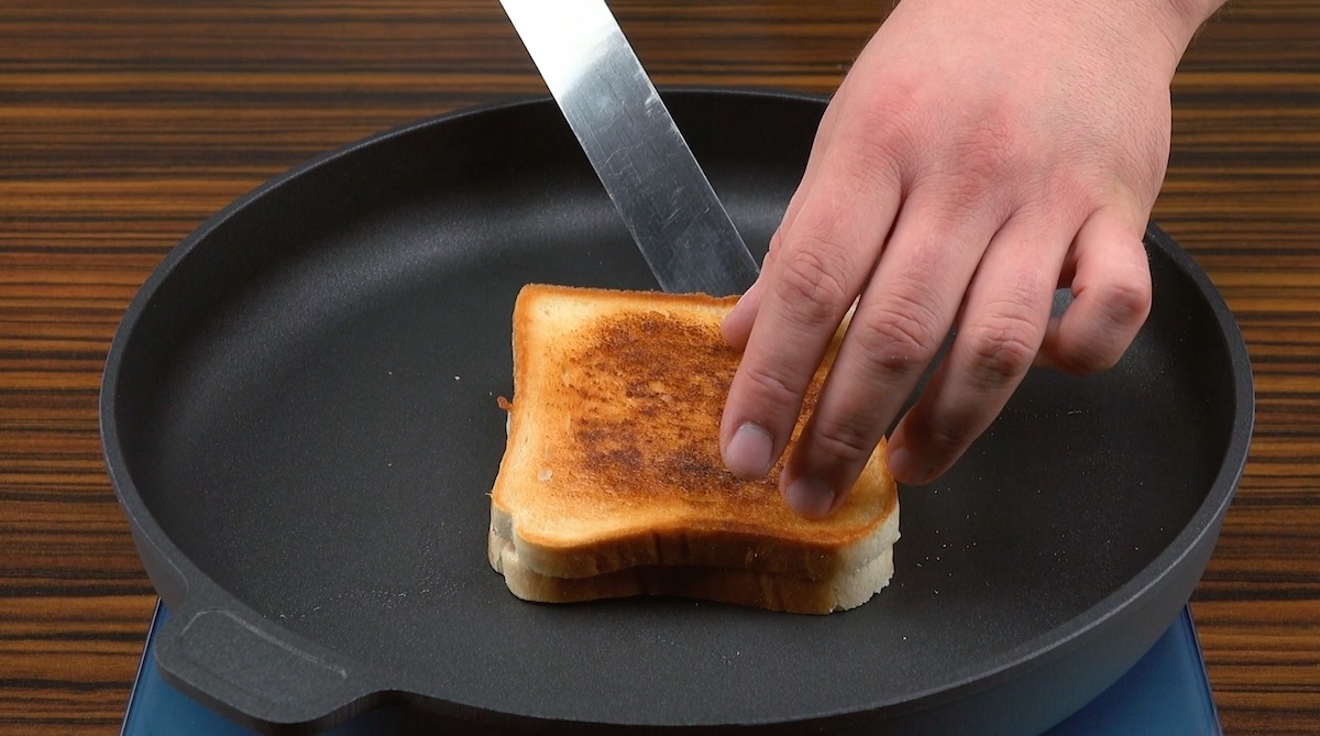 2 Scheiben Toast werden mit Cheddar und Mozzarella belegt, zusammengeklappt und in einer Pfanne angebraten