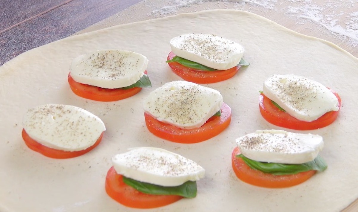 Mozzarellascheiben werden auf Tomatenscheiben und Basilikum gelegt