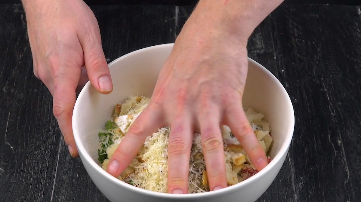 Hackfleisch wird mit GewÃ¼rzen, Paniermehl und Parmesan in SchÃ¼ssel  mit Hand vermengt