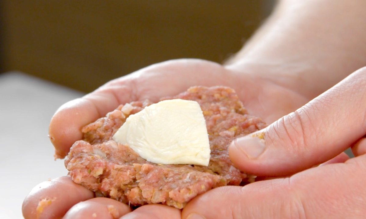 Ein Stück Mozzarella wird in Hackfleisch gelegt