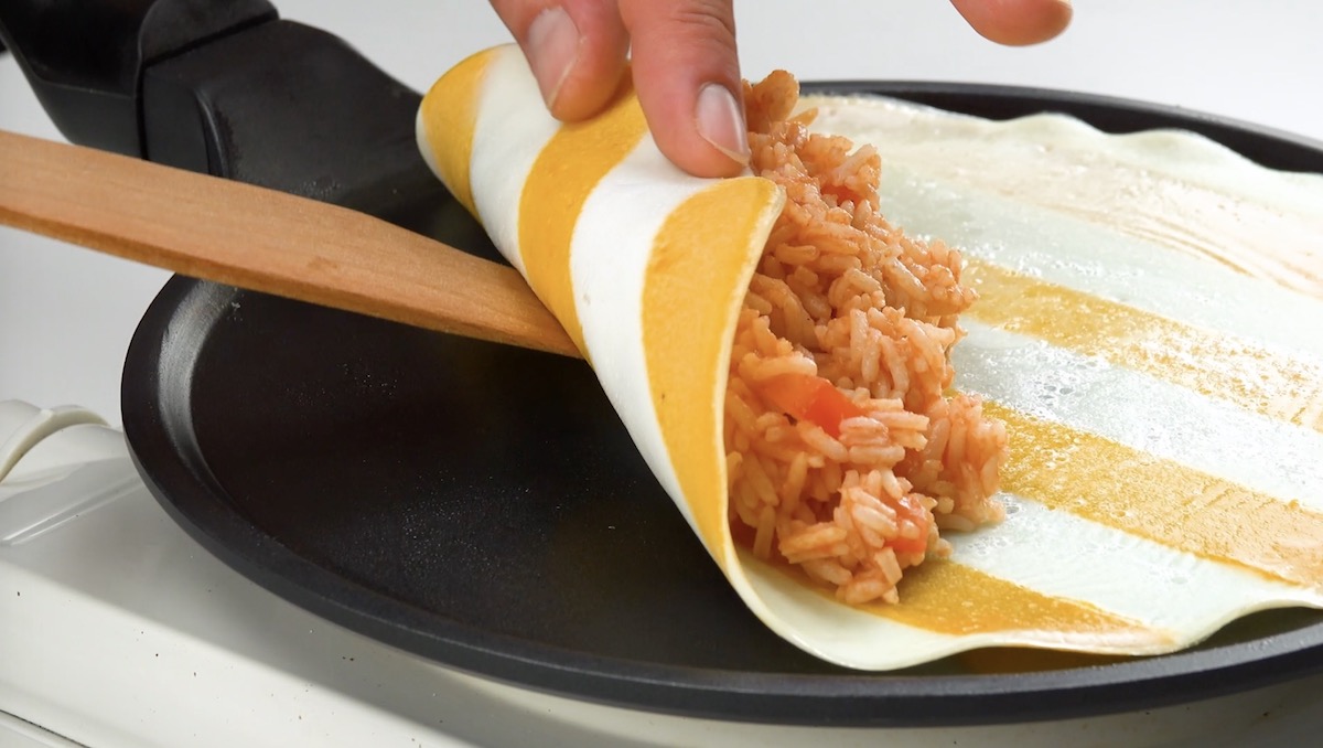 Das zweifarbige Omelett wird mit Tomatenreis gefÃ¼llt und aufgerollt