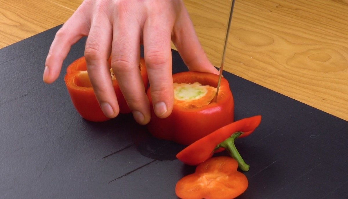 Das obere und untere Ende einer roten Paprika wird abgeschnitten und das KerngehÃ¤use entfernt