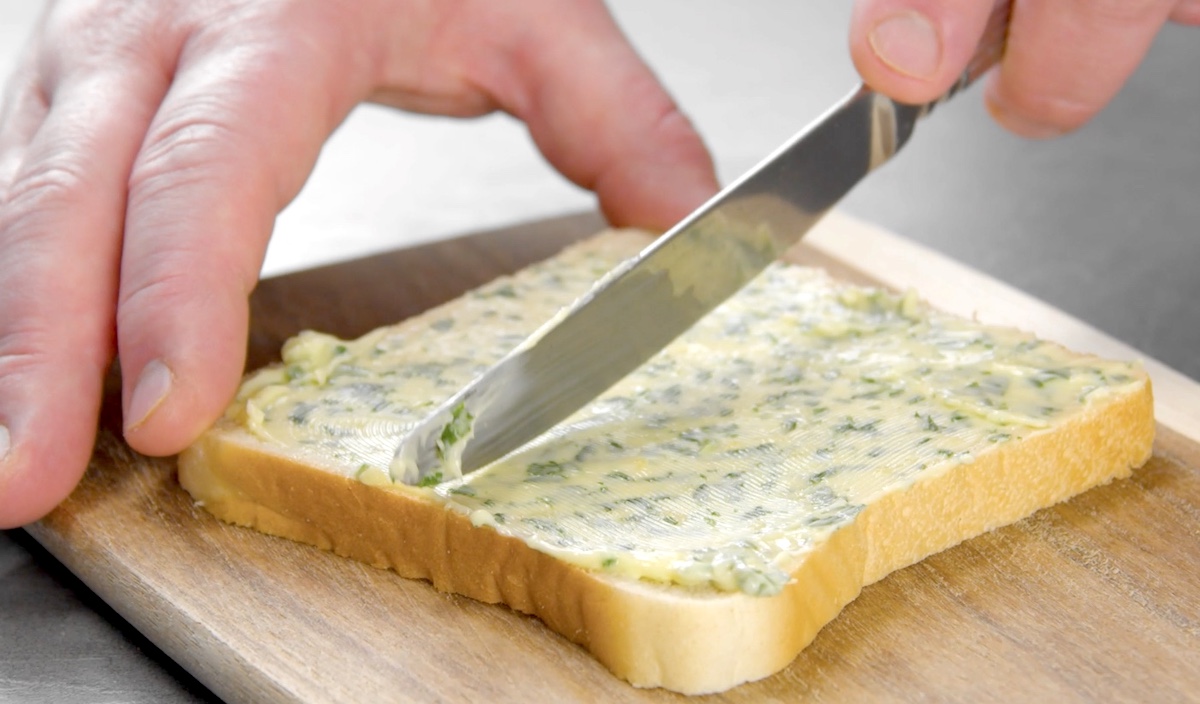 Ein mit Kräuterbutter bestrichenes Toast wird in der Mitte halbiert