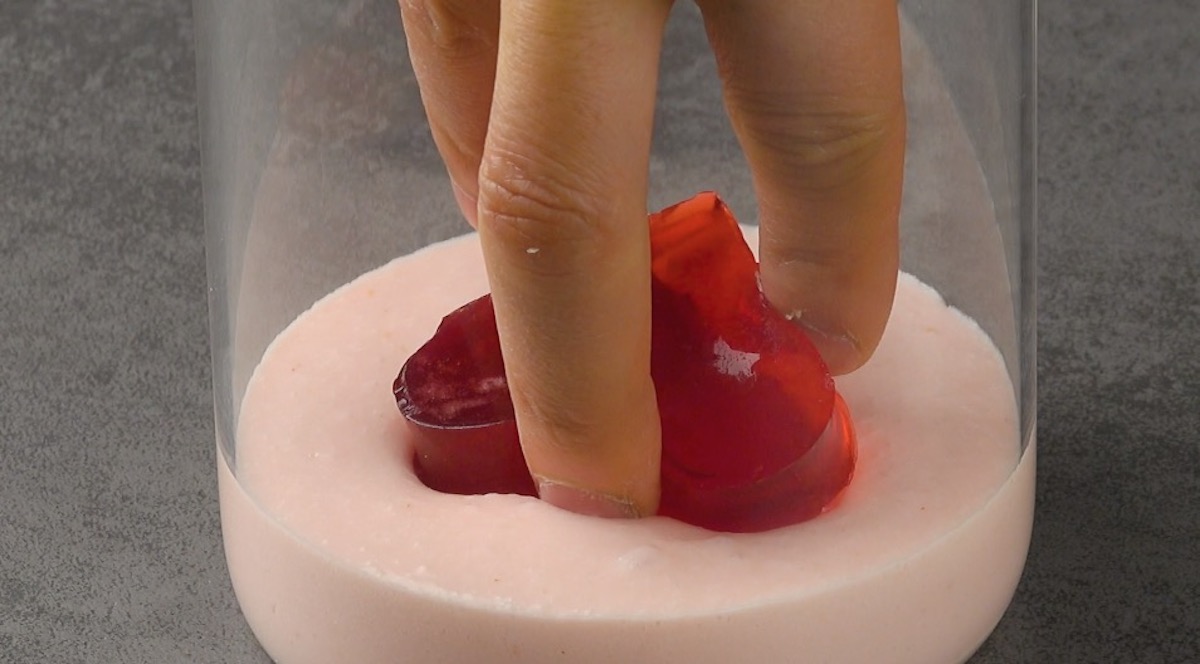 Die ausgestochenen Wackelpudding-Herzen werden in Erdbeer-Mousse in hohem Glas aufeinander gelegt