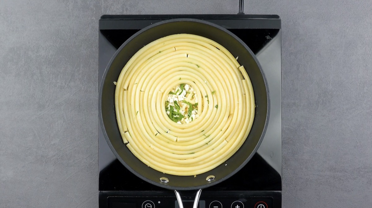 Eine weitere Schicht Nudeln wird spiralförmig auf eine Schicht Käse in Pfanne gelegt
