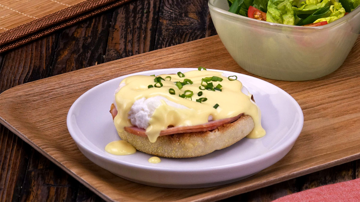 Ein Ei Benedict auf einem halbierten Toastbrötchen mit Kasseler und Sauce Holondaise.