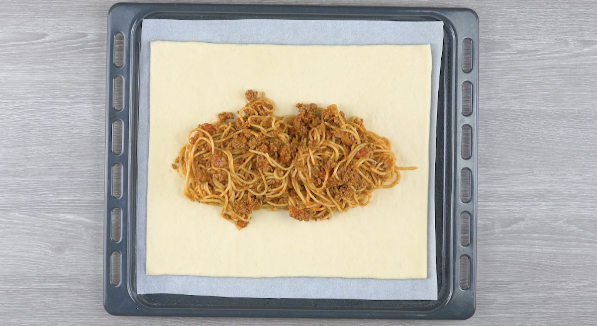 Spaghetti bolognese liegen in der Mitte von auf einem mit Backpapier belegtem Backblech