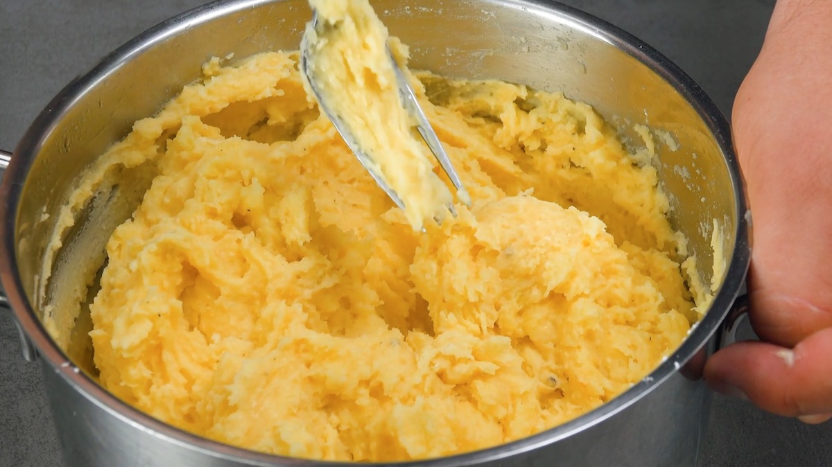 Gestampfte Kartoffeln werden in Topf mit Eigelben, Stärke und Semmelbröseln vermischt