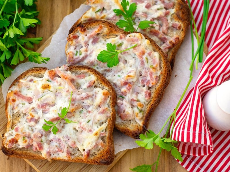 Mehrere Flammkuchen-Toasts, die halb übereinander liegen.