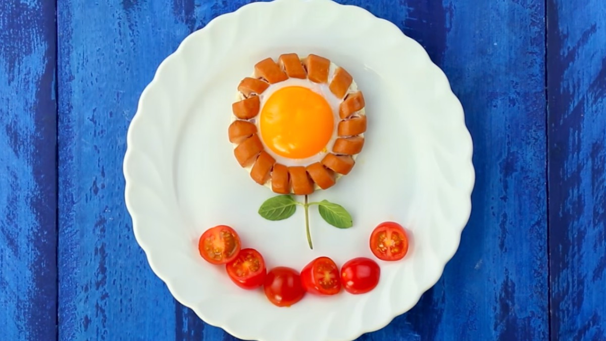 Würstchenring mit Spiegelei in der Mitte als Blume, dazu halbierte Tomaten