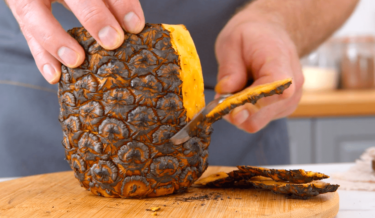 Eine gebackene Ananas wird geschÃ¤lt