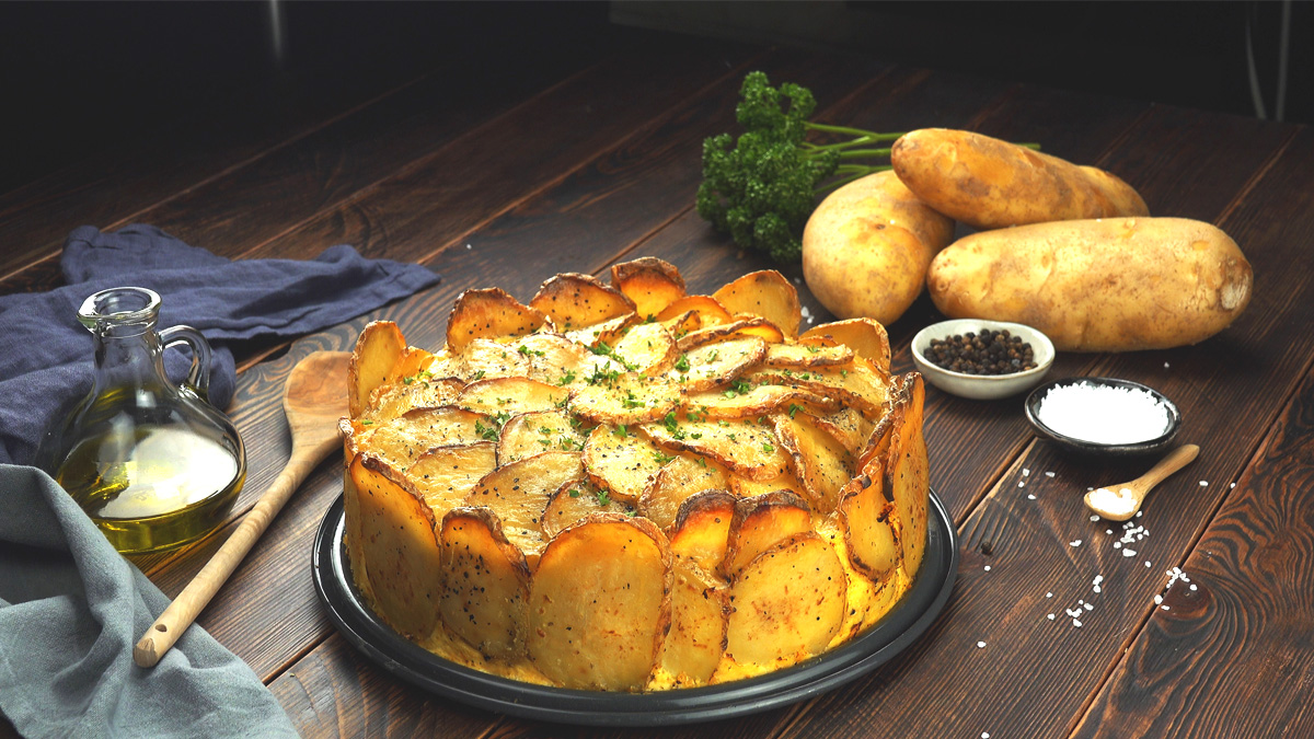 Ein Kartoffelkuchen, neben dem Zutaten und Schälchen mit Peffer und Salz sind.