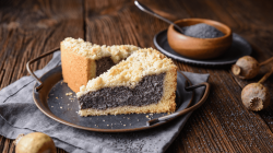 Zwei Stücke Mohnkuchen mit Streuseln auf einem Teller, daneben eine Schale mit Mohnkörnern