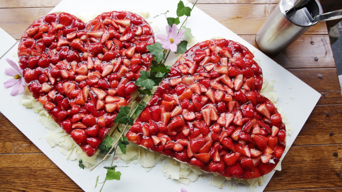 Zwei Muttertagskuchen mit Erdbeeren in Herzform.