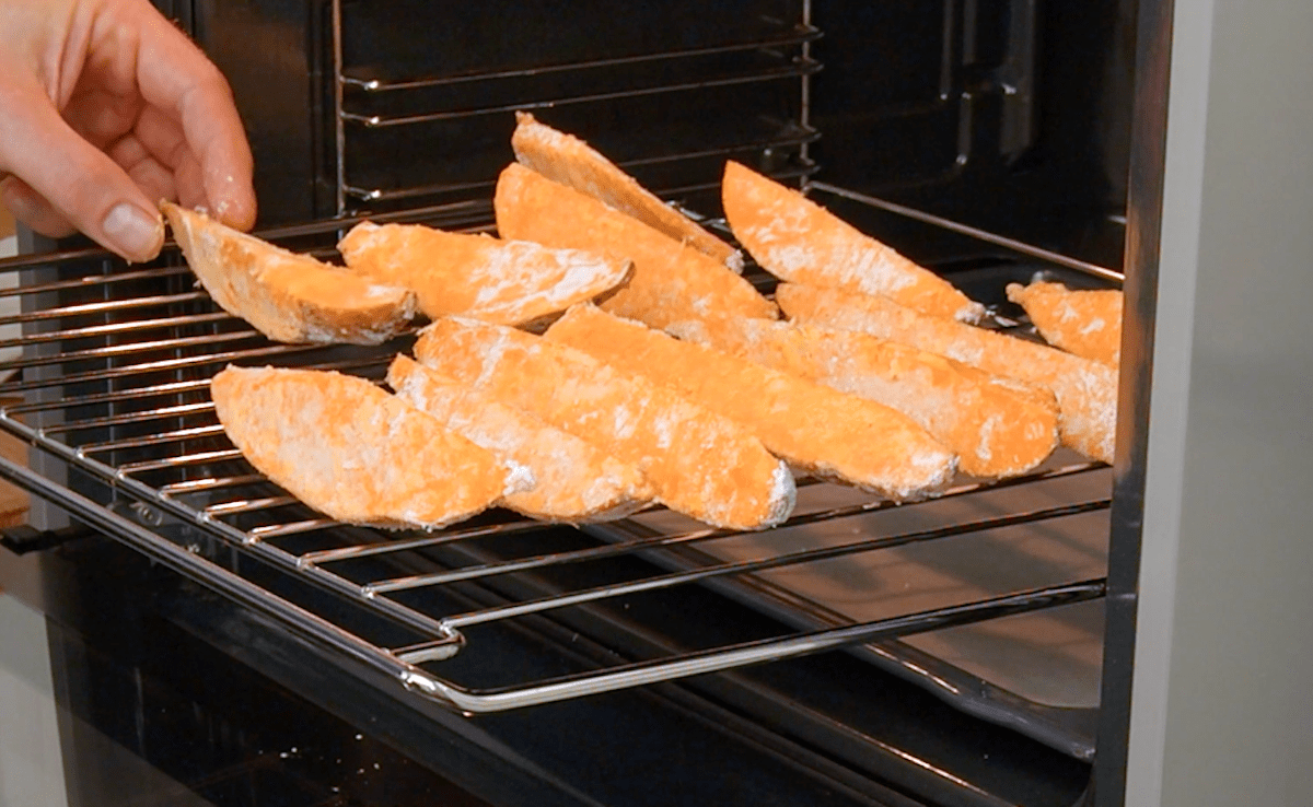 SÃ¼ÃŸkartoffel-Spalten werden auf einem Rost in einen Ofen geschoben