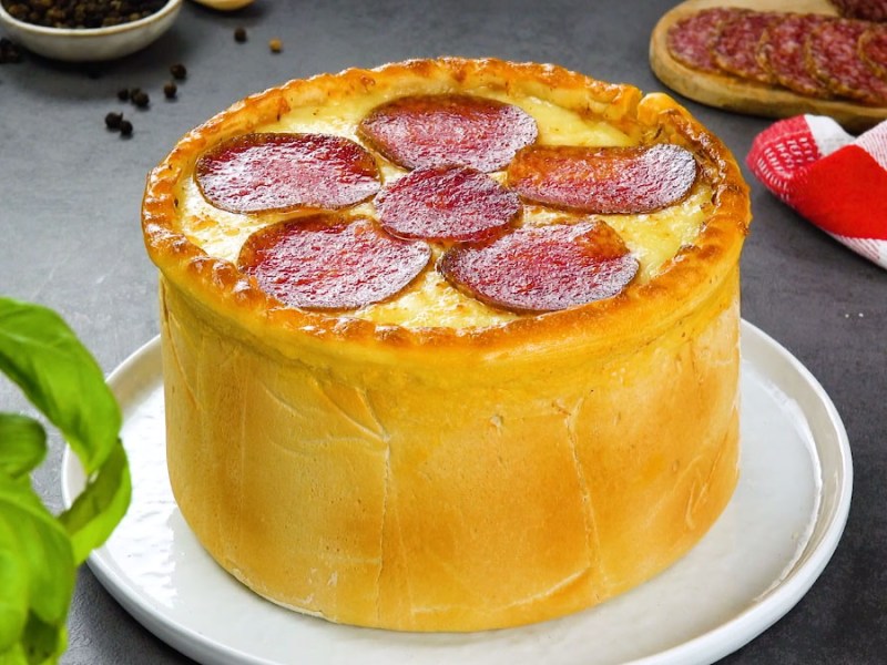 Ein Pizzakuchen mit Salami auf einem Teller.