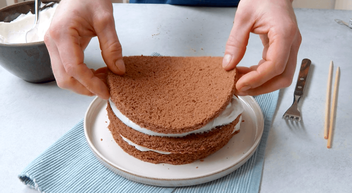 Drei gleich große Kuchenplatten werden zu einer Schokoladentorte geschichtet.