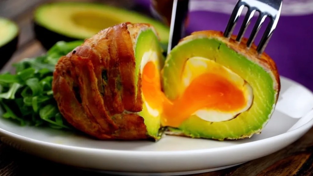 Ein Avocado-Ei auf einem Teller, das durchgeschnitten wird.