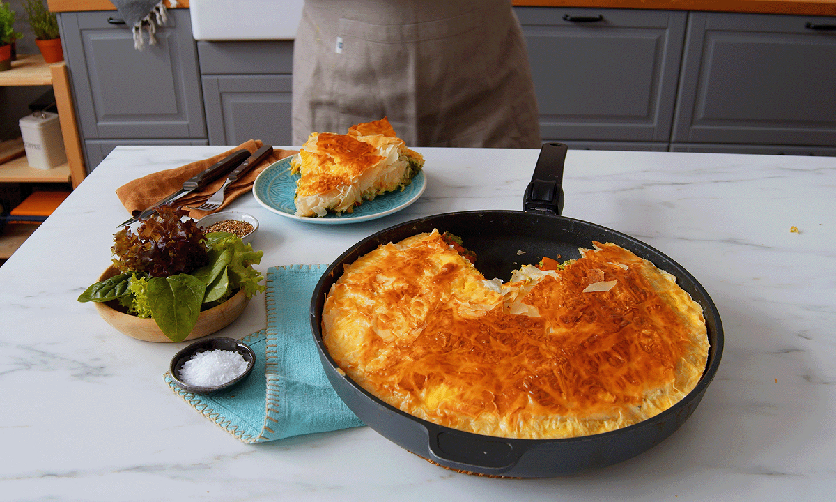 Eine herbstliche Börek-Pfanne mit Kürbis und Yufka-Teig auf einer Küchentheke, daneben eine Schale Salz und ein Teller mit einem Stück des Auflaufes.