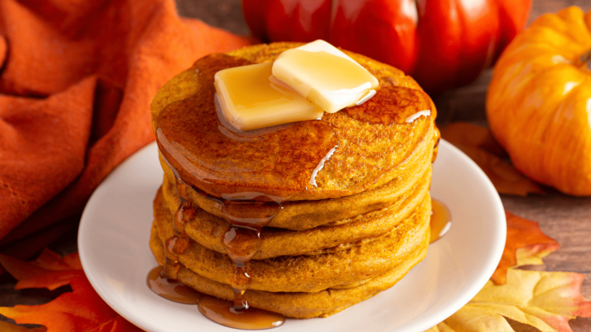 Ein Stapel KÃ¼rbis-Pancakes mit Butter und flÃ¼ssigem Honig