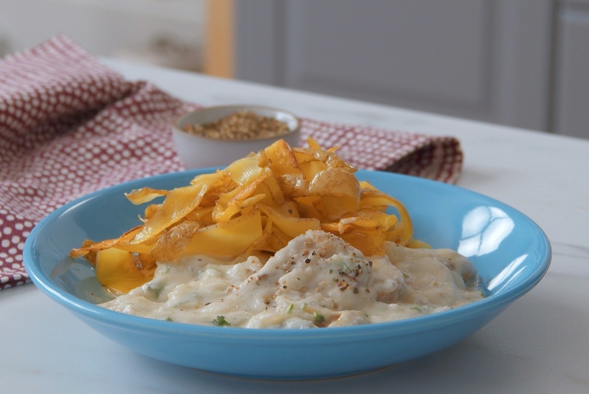 Schweinefilet in Blumenkohlsoße mit Kartoffelnudeln, serviert auf einem blauen Teller.