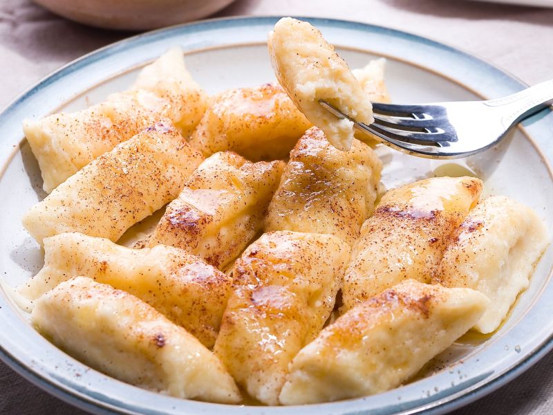 Bratapfel-Gnocchi mit Zimt und Zucker in einem tiefen Teller. Eine Gnocchi ist aufgespießt auf einer Gabel.